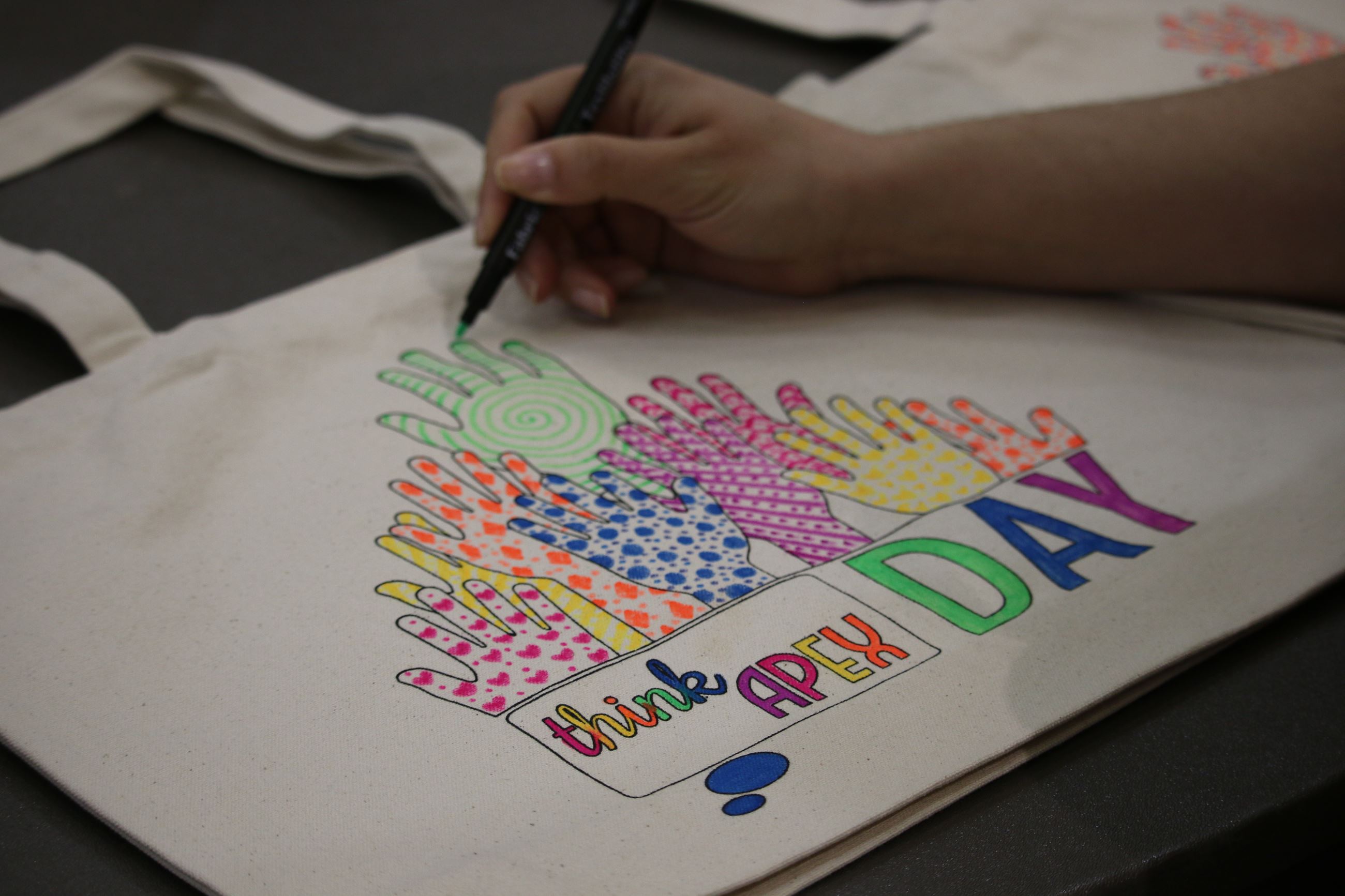 A volunteer coloring a tote bag